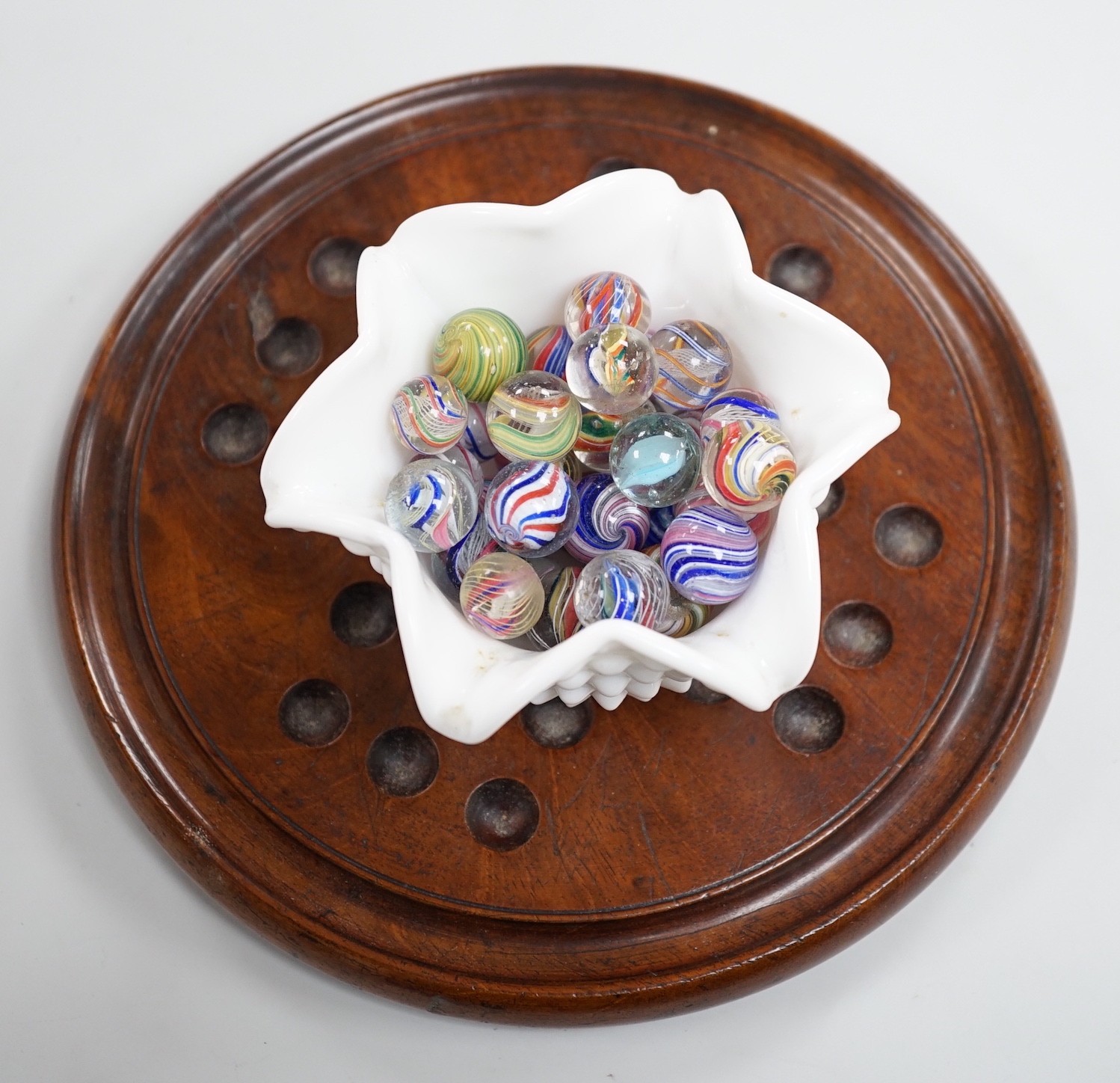 A mahogany solitaire board with a collection of latticino and marbled glass marbles